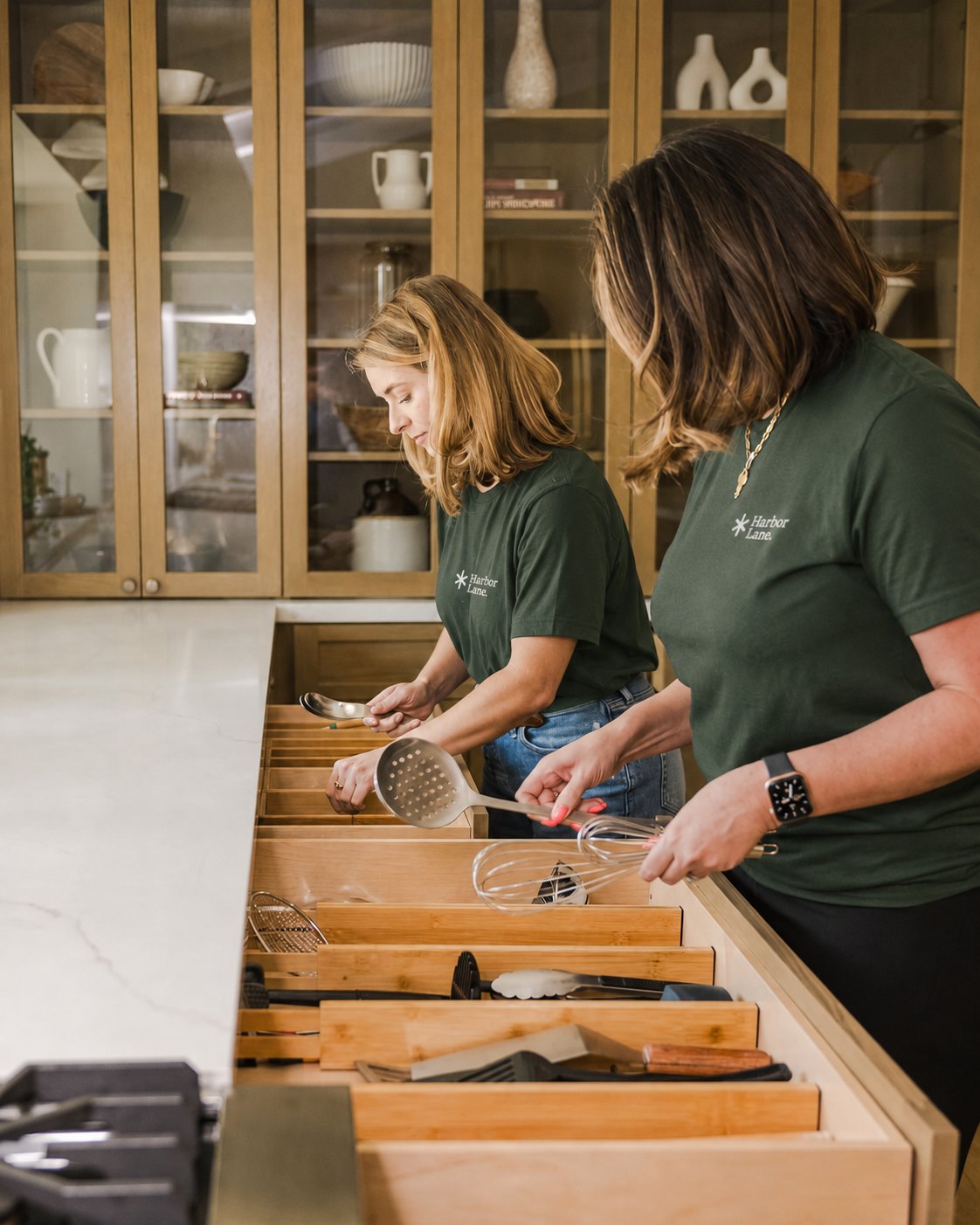 Two Harbor Lane team members organizing kitchen drawers.