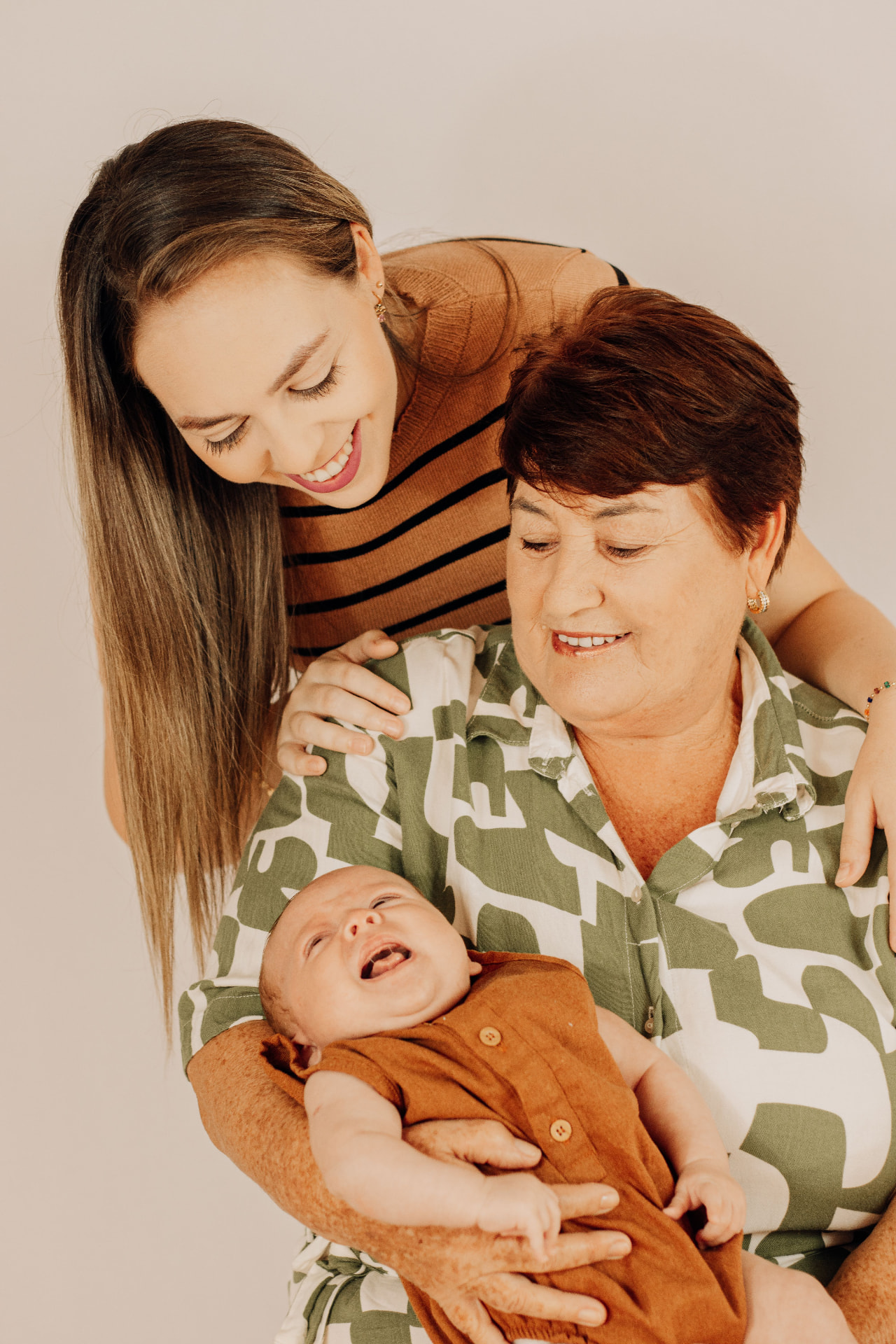 Three generations of a family together at home, a grandmother holding a newborn.